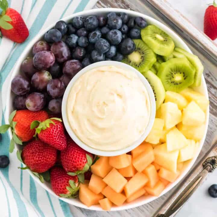 Cream cheese fruit dip on a platter surrounded by fresh fruit.