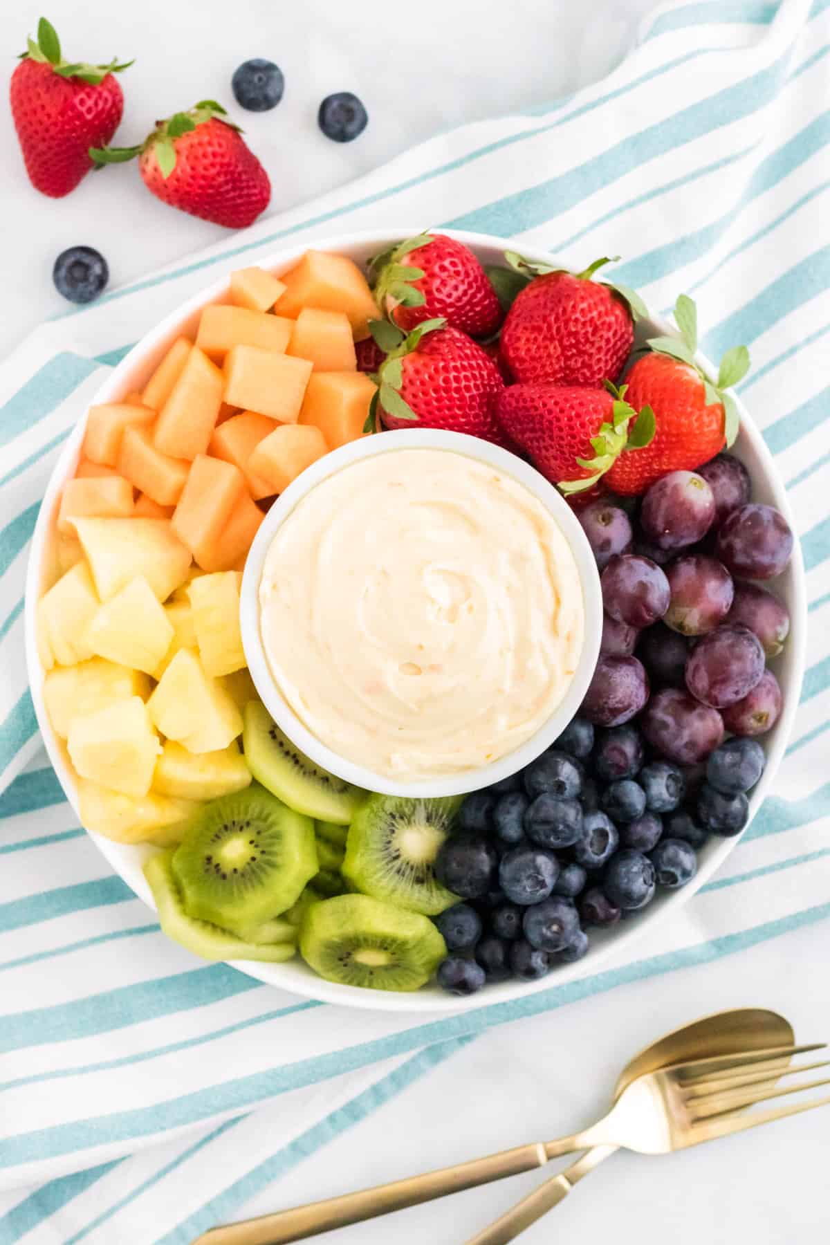 Cream cheese fruit dip on a platter surrounded by fresh fruit.