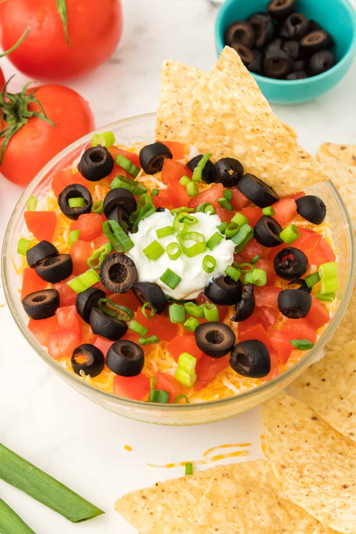 Bowl of layered taco dip served with tortilla chips.