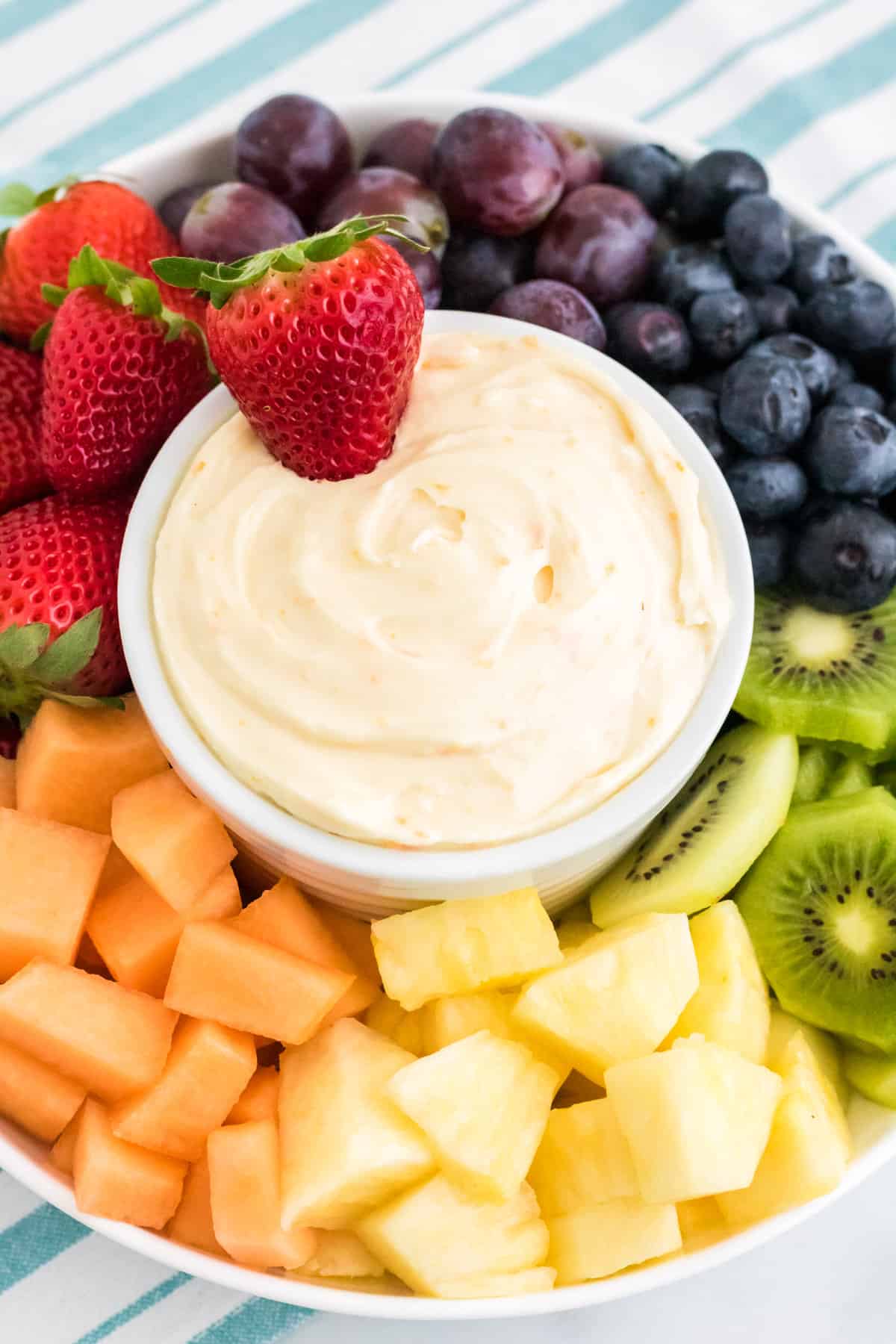 Fresh fruit and dip platter with strawberry sticking out of the orange fruit dip.