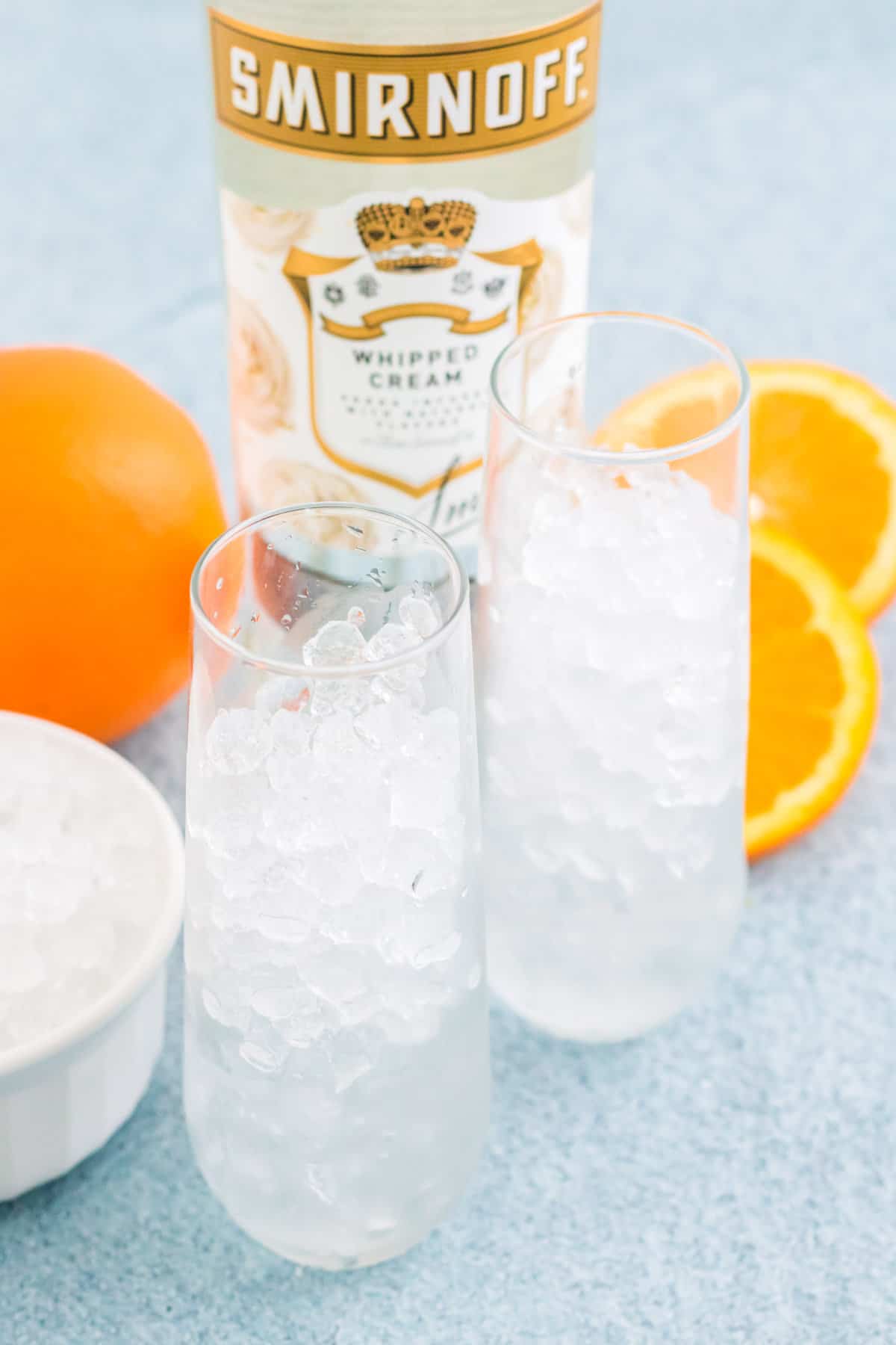 Two tall cocktail glasses frilled with crushed ice cubes.