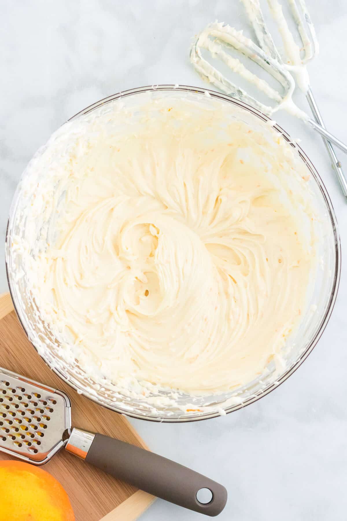 Large glass bowl with whipped cream cheese fruit dip. Hand mixer beater attachments are next to the bowl.