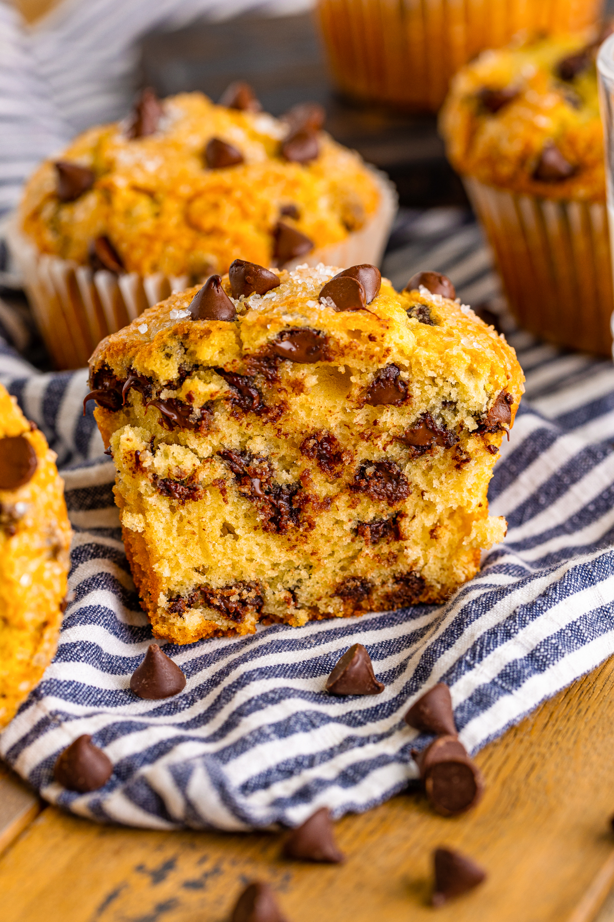 Bakery style jumbo chocolate chip muffin, broken open to show how it is packed with chocolate chips.