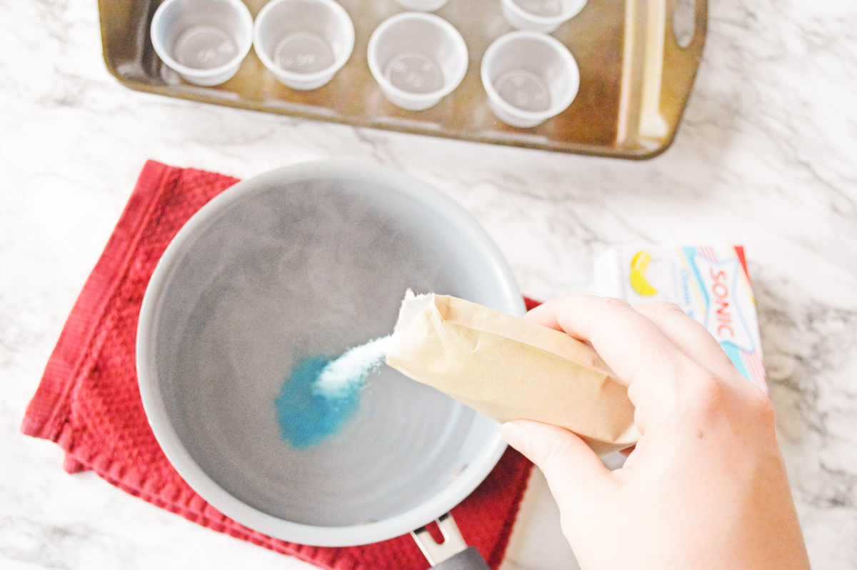 Blue ocean water jello mix being made with boiling water in a small saucepan.