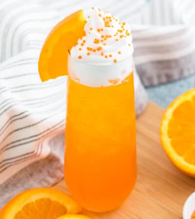 Orange creamsicle cocktail topped with whipped cream and fresh orange slice.