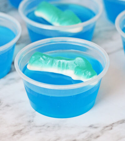 Shark jello shot with blue gelatin and shark gummy candy on top.