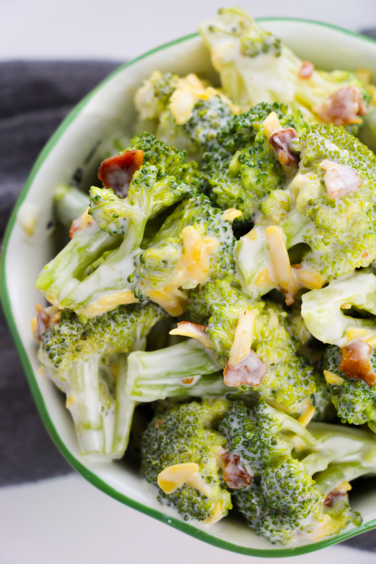 Top-down photo of broccoli salad with crumbled bacon and shredded cheddar cheese.