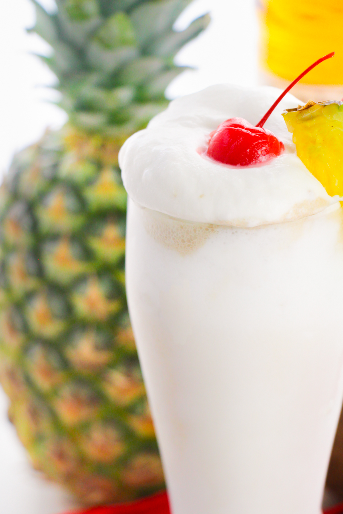 Pina colada with fresh pineapple in the background.