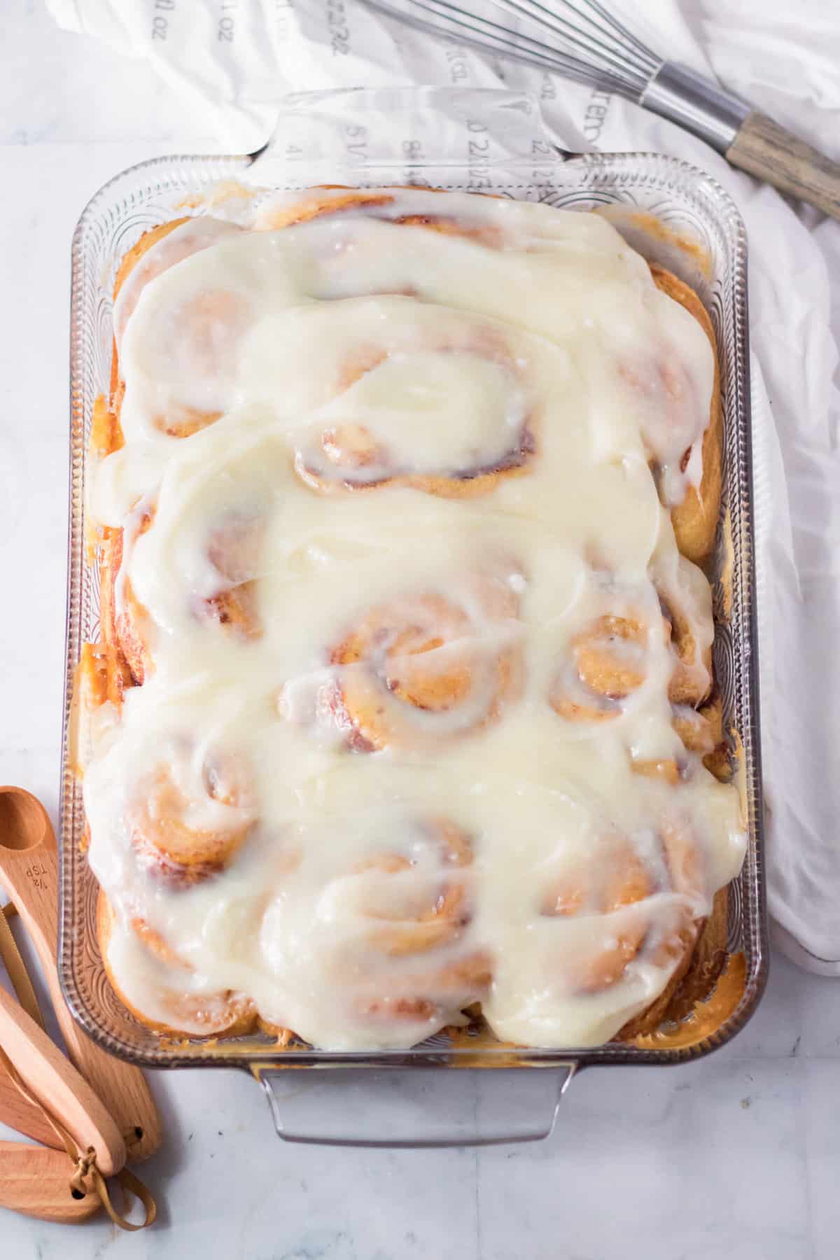 Cinnamon rolls with cream cheese frosting in a glass casserole dish.