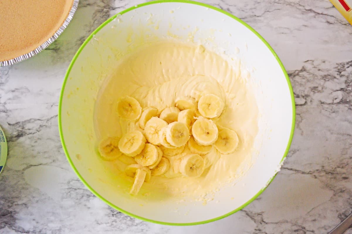 Sliced bananas adding to mixing bowl.