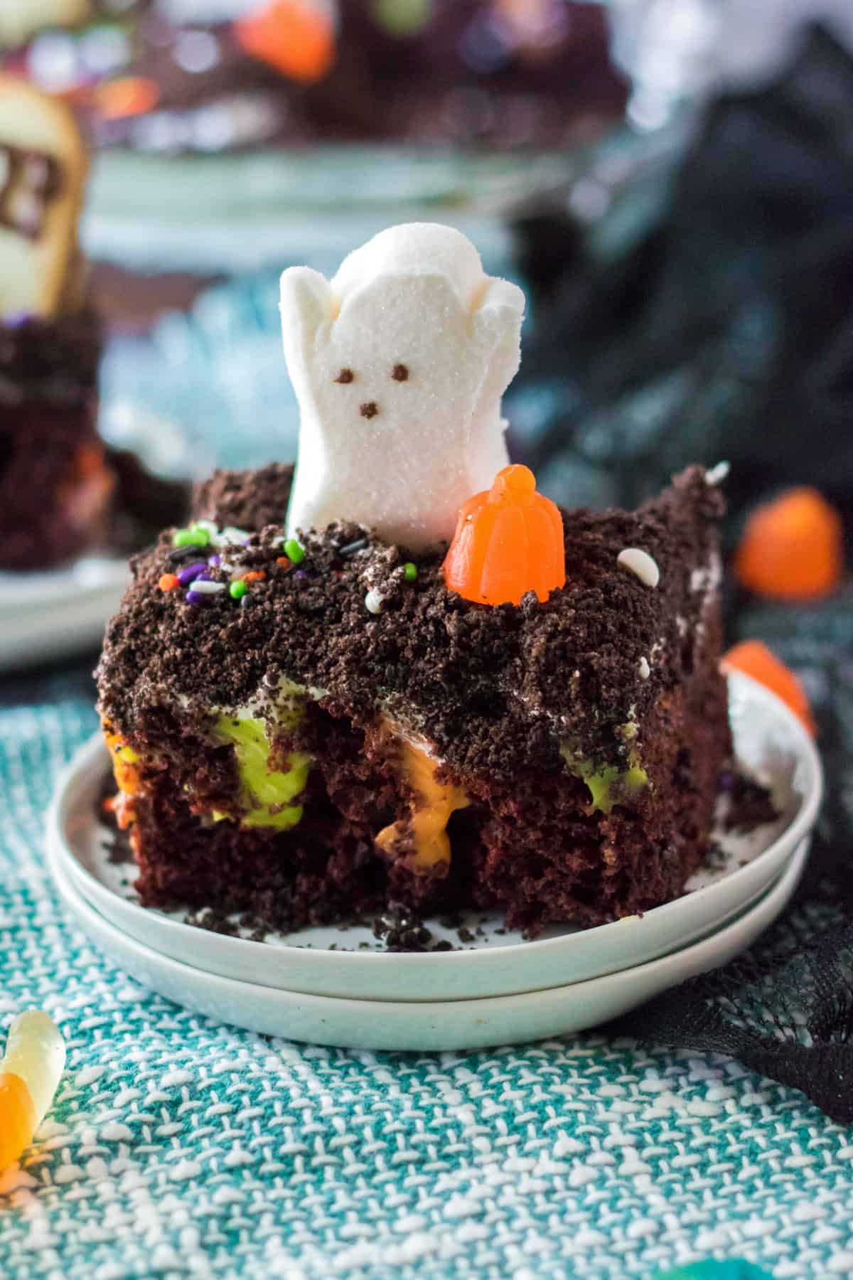 Piece of halloween poke cake with ghost and pumpkin candy on top.