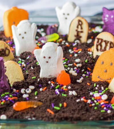 Ghosts in the Graveyard Dessert topped with peeps ghosts, cookie tombstonea, and other Halloween candy.