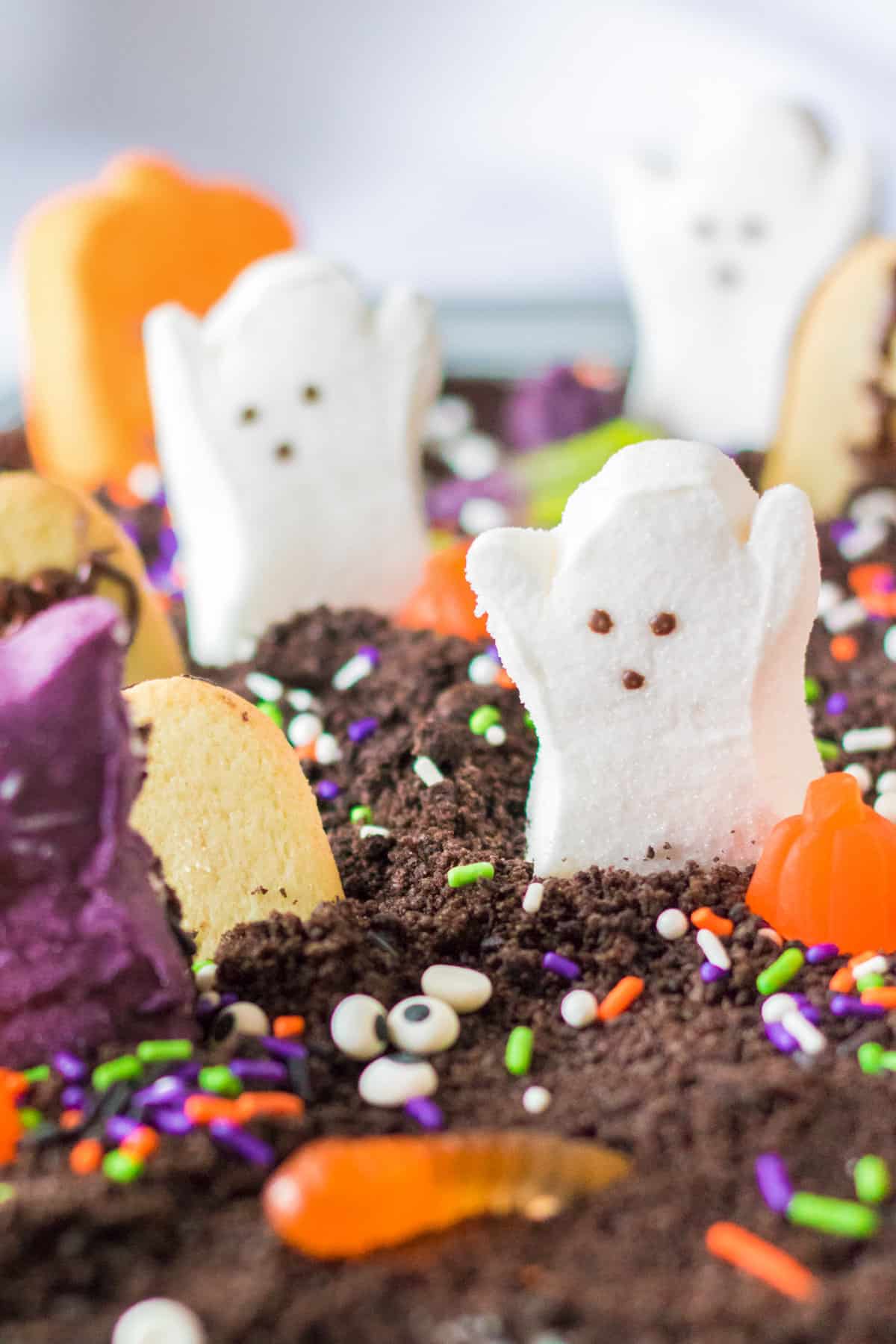 Cake covered with oreo cookie crumbs and topped with Halloween Peeps and other candies.