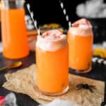 Hocus pocus punch - an orange drink topped with rainbow sherbet and a black and white paper straw.