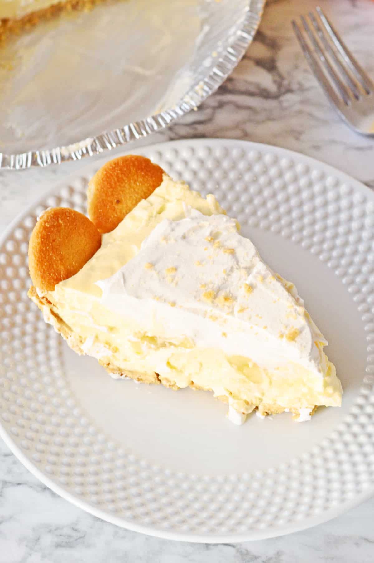 Slice of banana cream pudding pie on white plate.