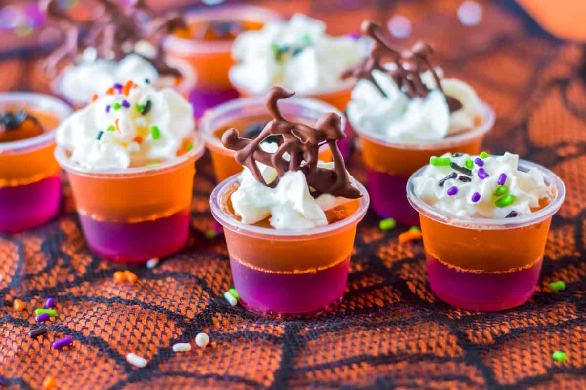 Halloween layered jello shots with whipped cream chocolate webs.