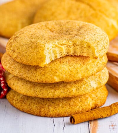 Soft and chewy snickerdoodle cookies piled on top of one another with a bite taken out of top cookies.