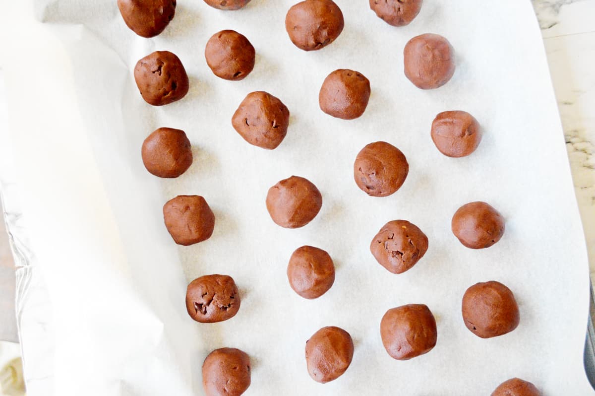 Balls of chocolate cookie dough on baking sheet.