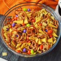 A festive halloween chex mix recipe with pretzels, chex cereal, bugles, M&Ms, and Reese's Pieces.