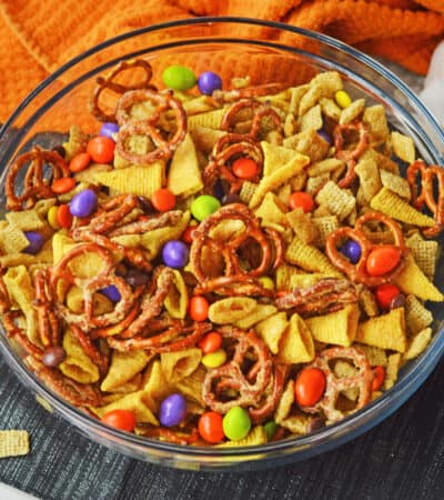 A festive halloween chex mix recipe with pretzels, chex cereal, bugles, M&Ms, and Reese's Pieces.