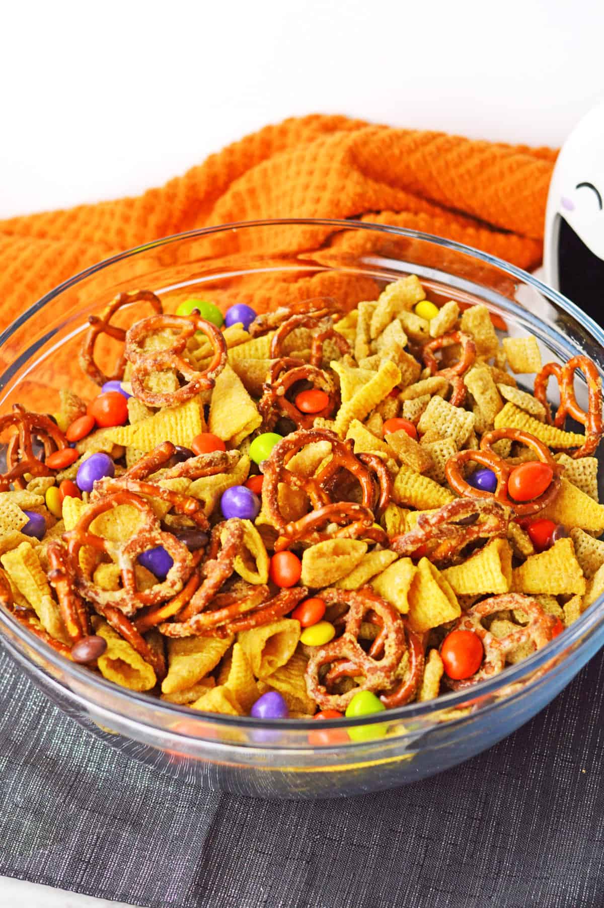 Halloween chex mix in glass bowl with halloween decor.