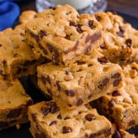 Peanut butter chocolate chip cookie bars piled on a plate.