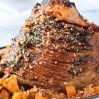 Pecan Glazed Ham with sweet potatoes in serving dish.