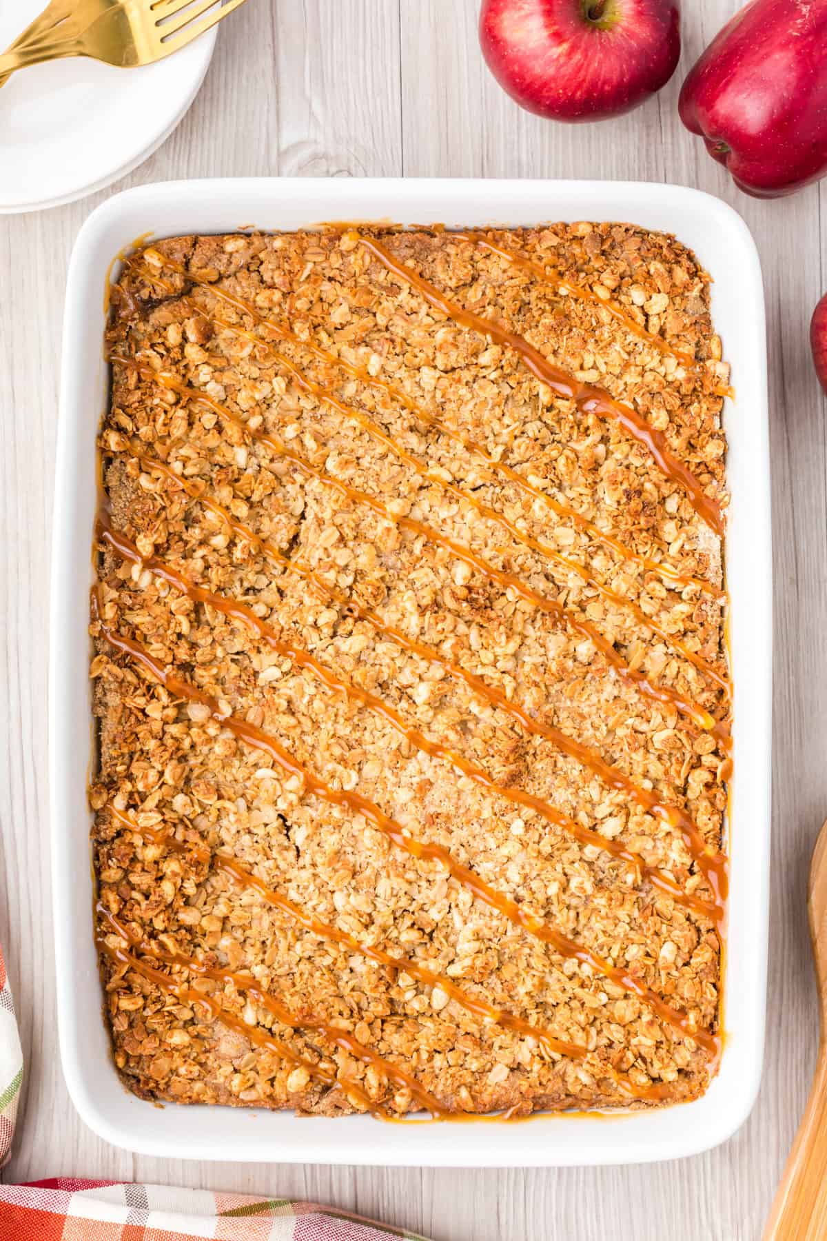 Apple crisp with oat granola and caramel drizzle in a rectangular baking pan.