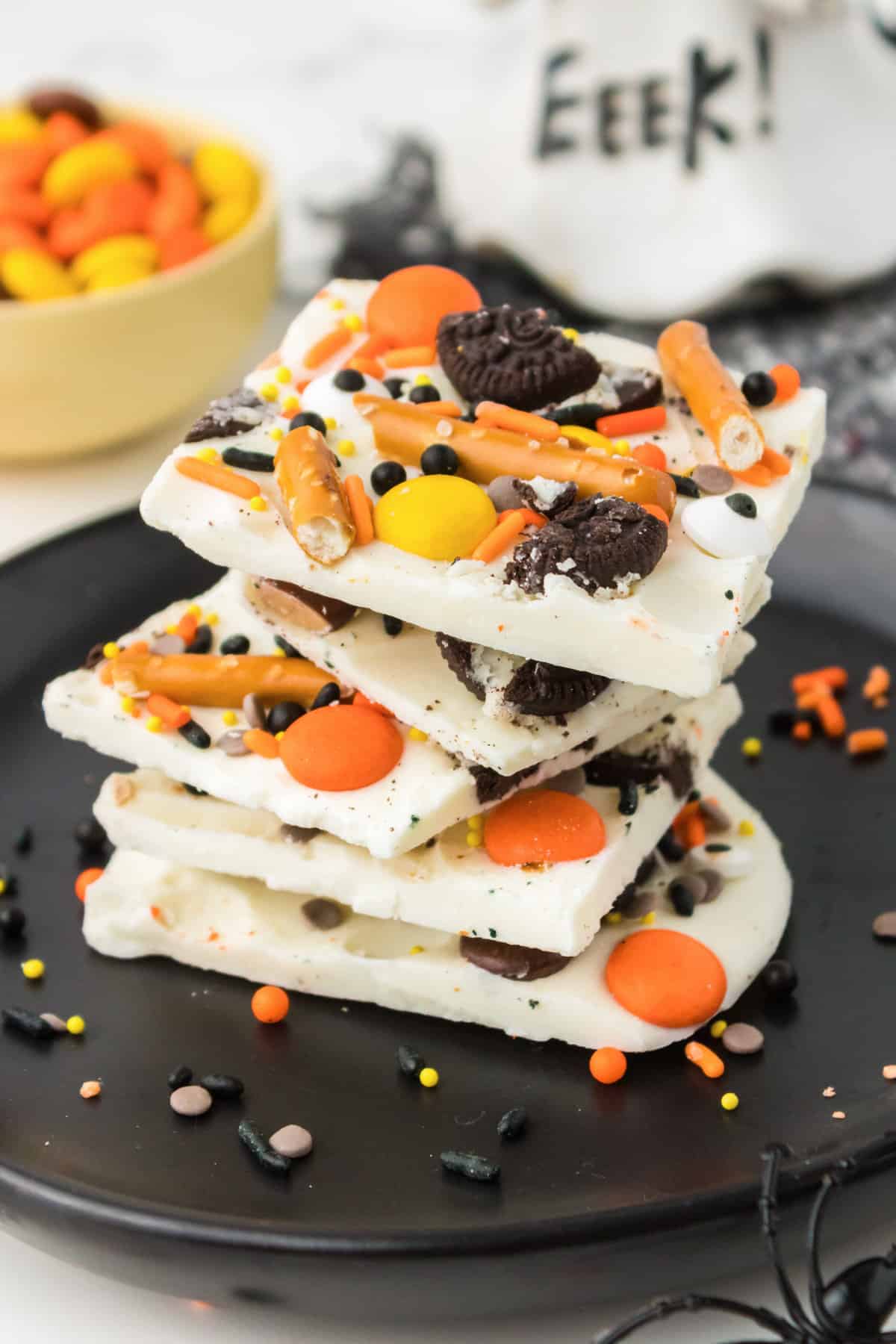 Pieces of Halloween Bark stacked on a black plate.
