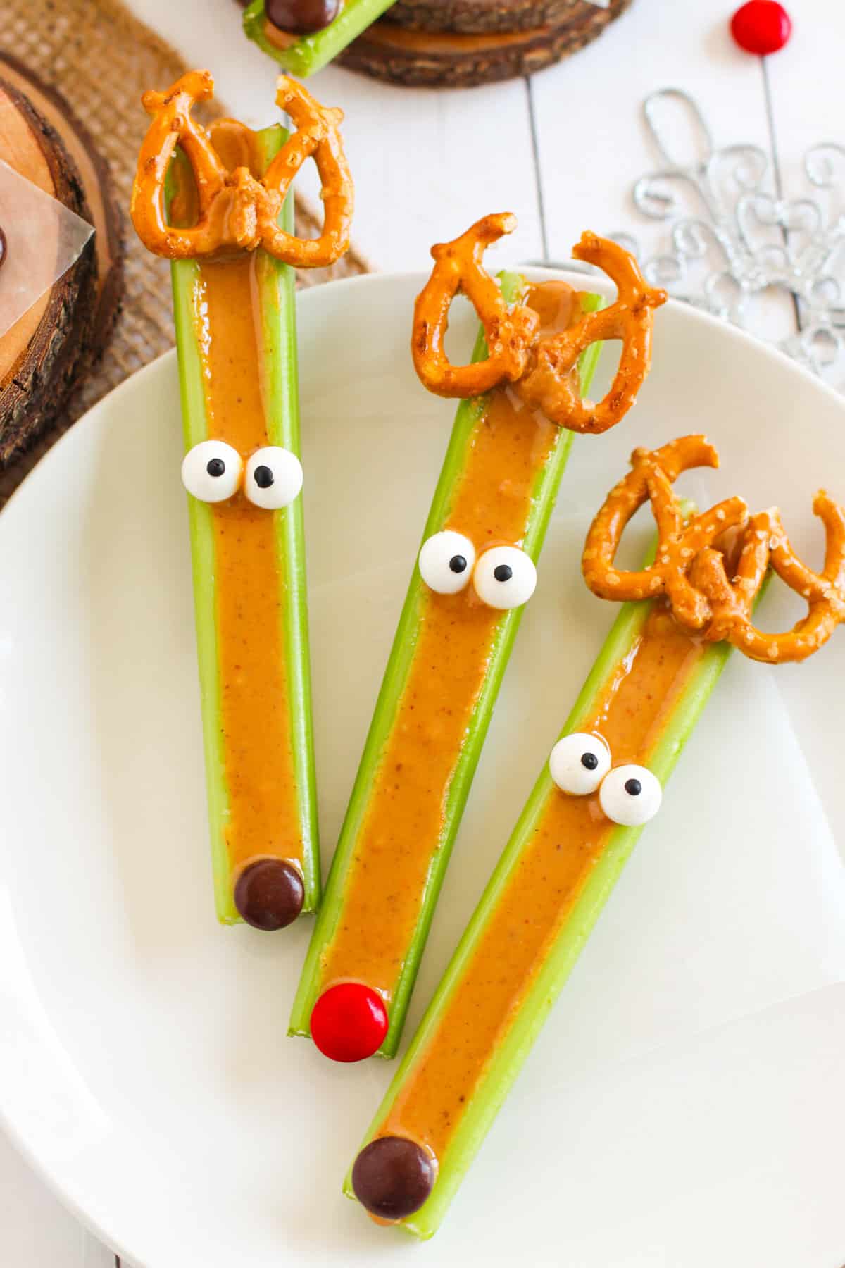 Three peanut butter celery sticks decorated to look like reindeer. 