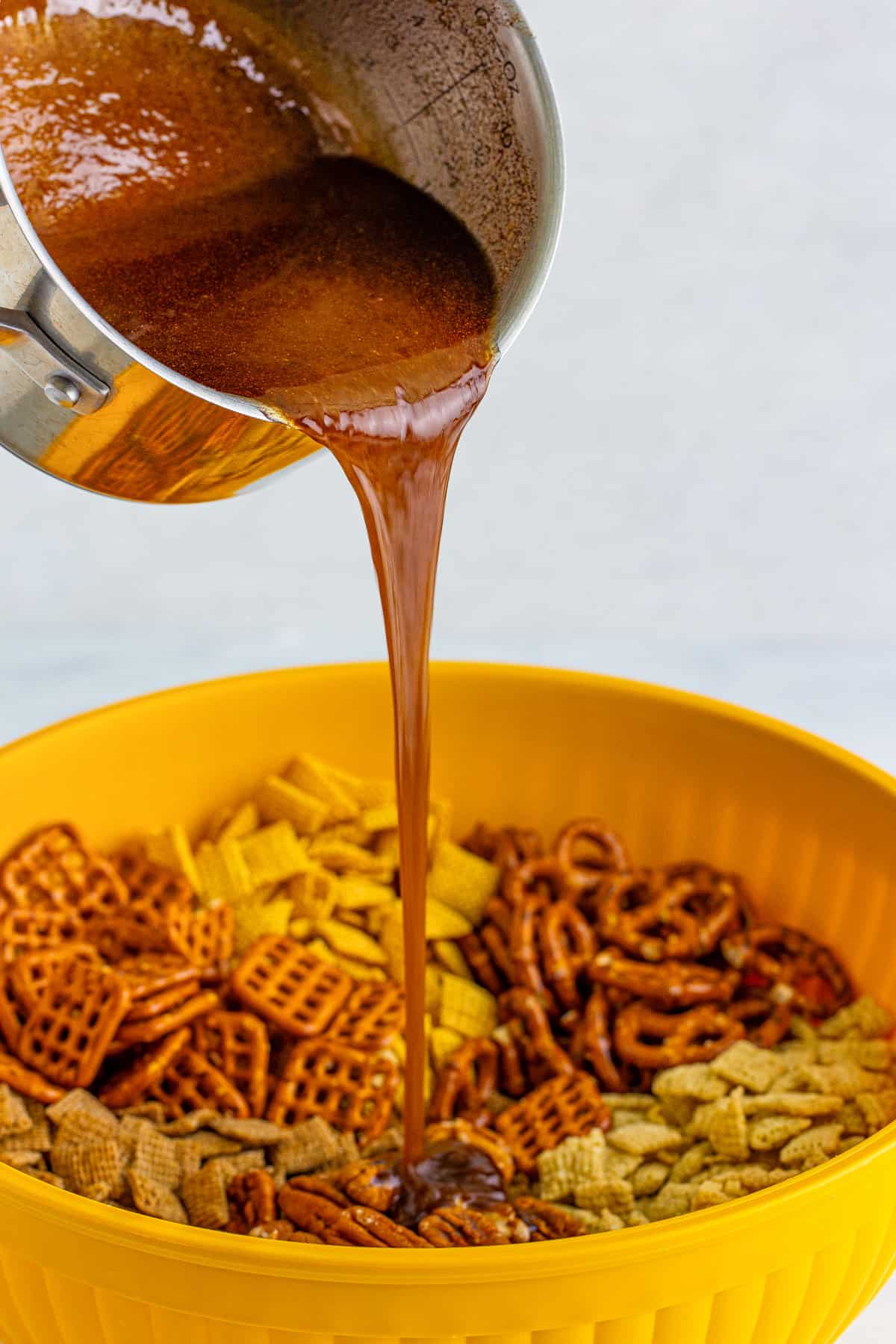 Cinnamon sugar and butter mixture being poured over chex mix.