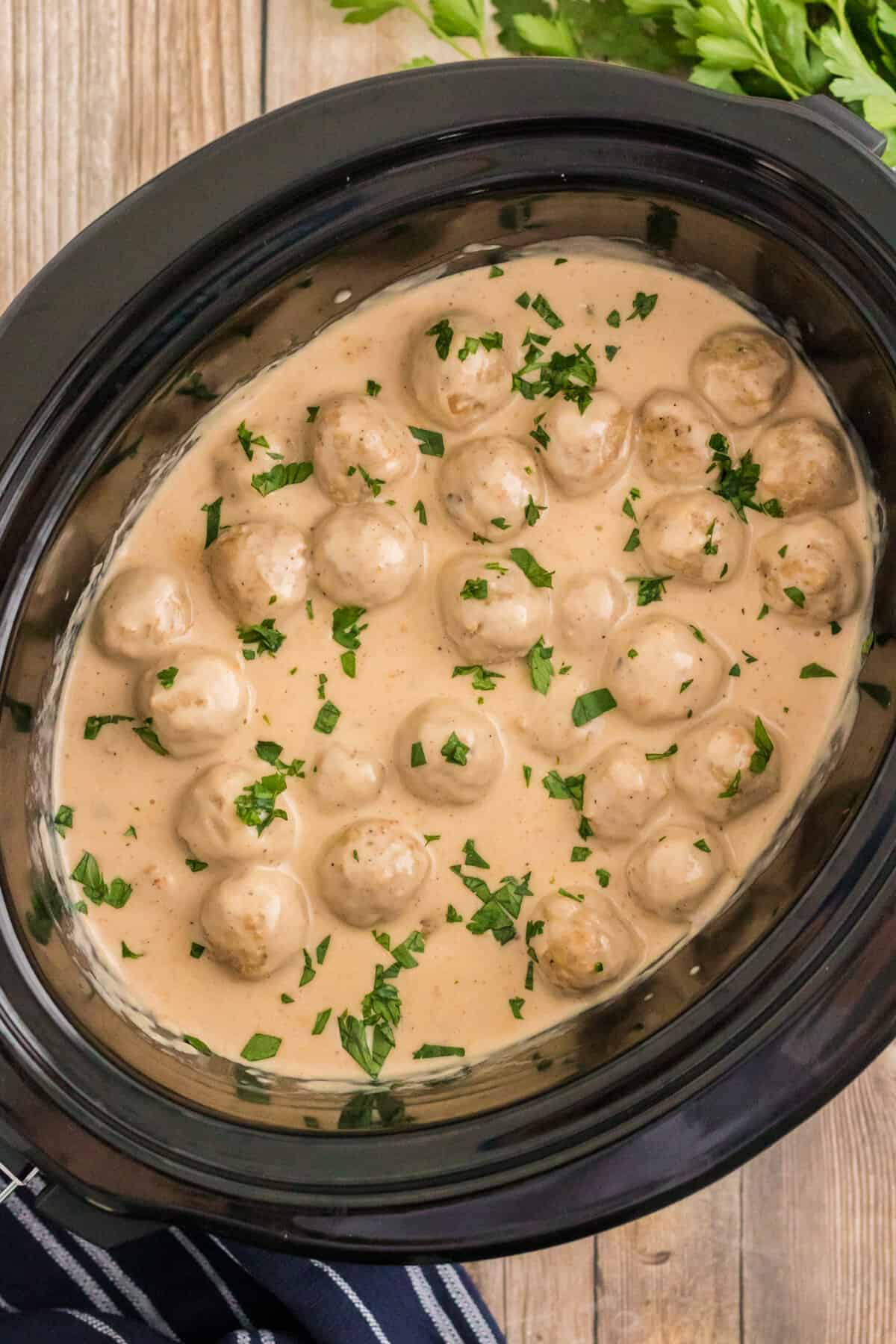Swedish Meatballs in slow cooker topped with chopped parsley.
