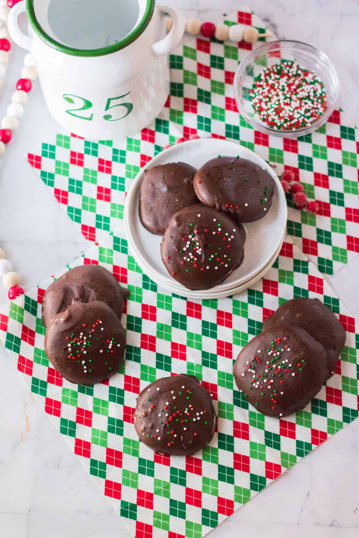 Copycat york peppermint patties with Christmas sprinkles on white plate and around plate on holiday napkin.