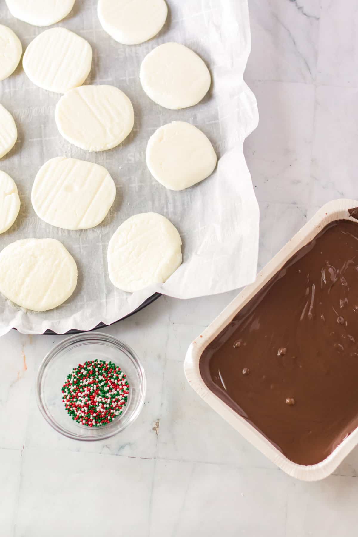 Frozen peppermint discs with melted almond bark and sprinkles next to them.