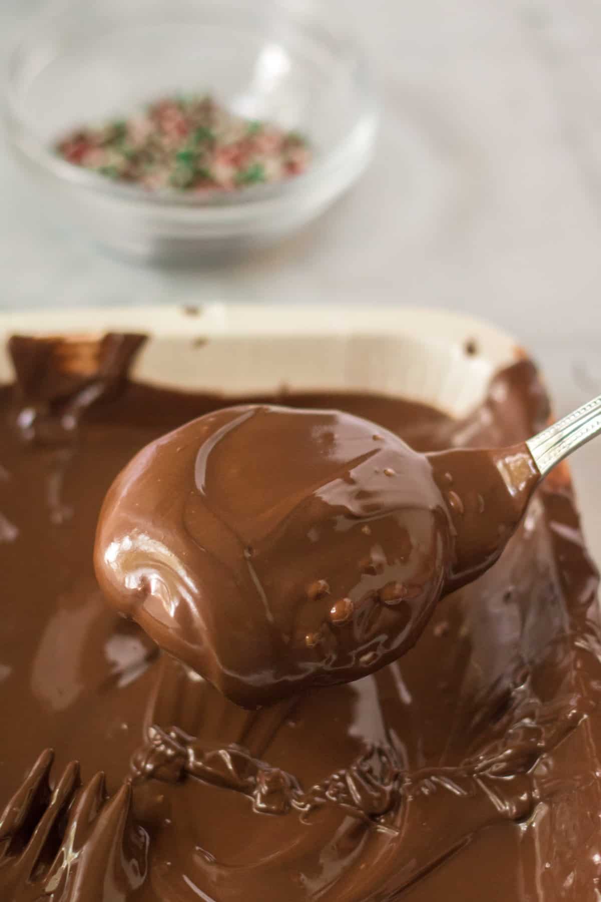Homemade peppermint patties being dipped in melted chocolate. 