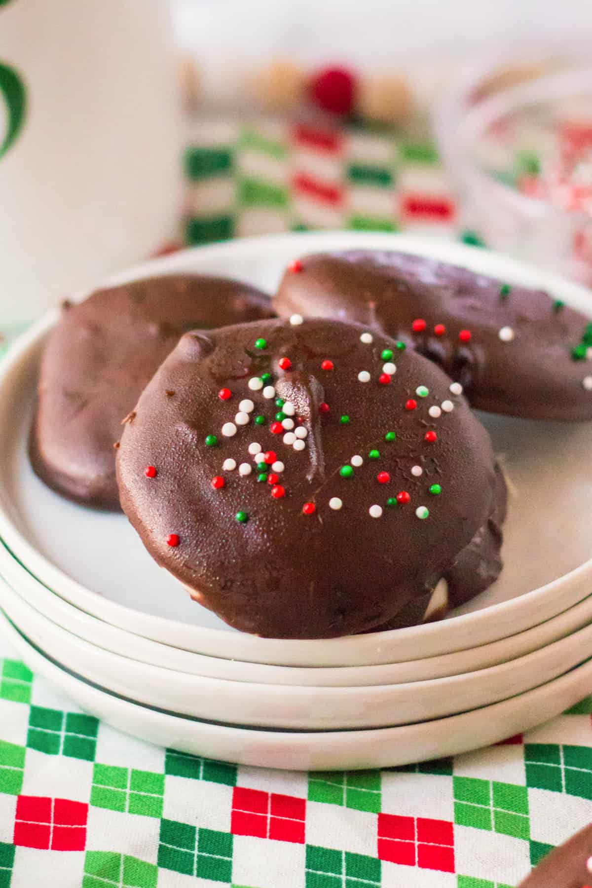 Homemade chocolate mint candy with Christmas sprinkles on white plate.