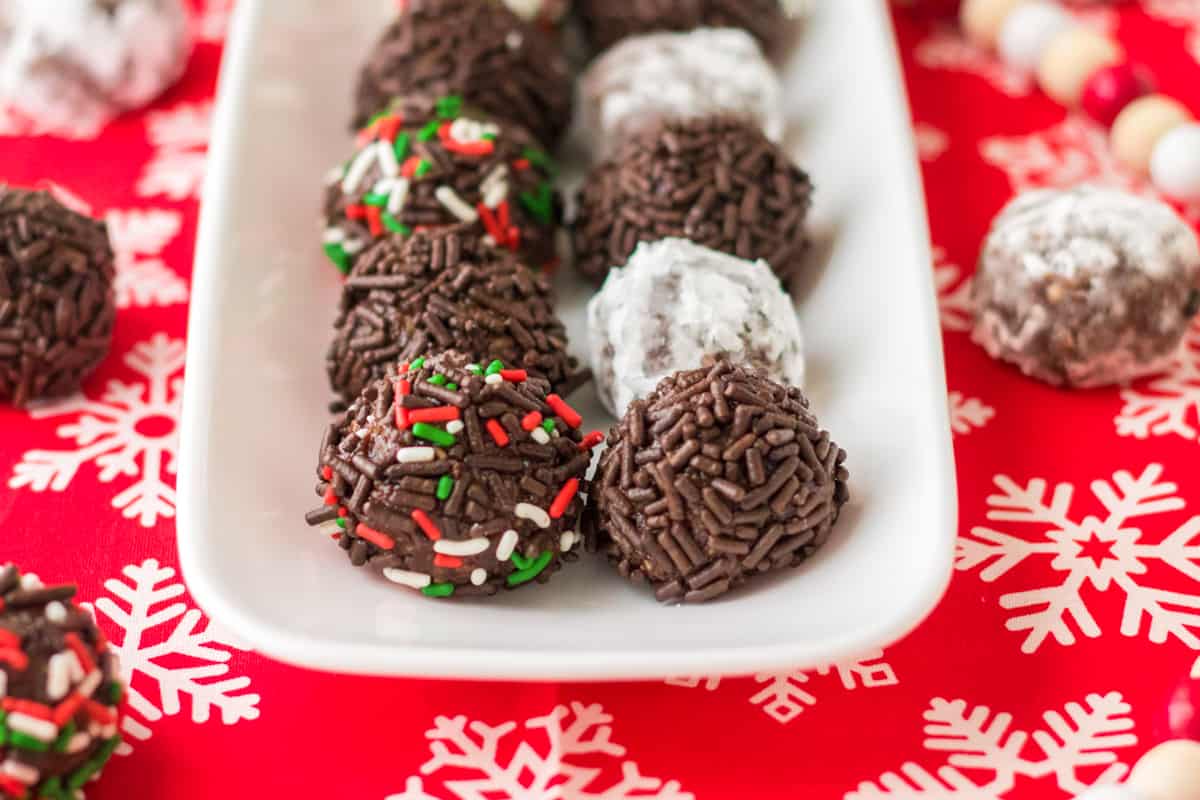 No bake chocolate rum balls served on white tray with Christmas decor.