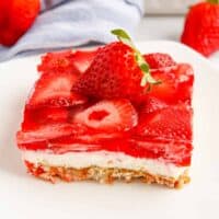 Square piece of strawberry pretzel salad topped with a fresh strawberry.