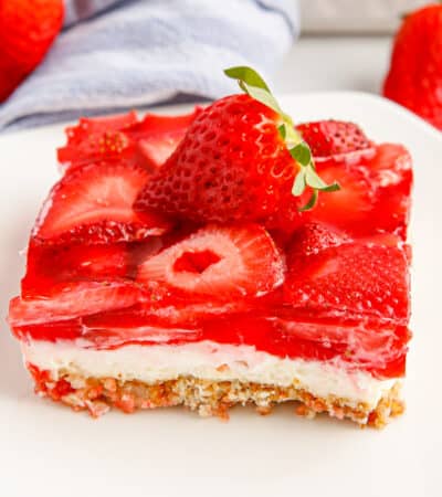 Square piece of strawberry pretzel salad topped with a fresh strawberry.