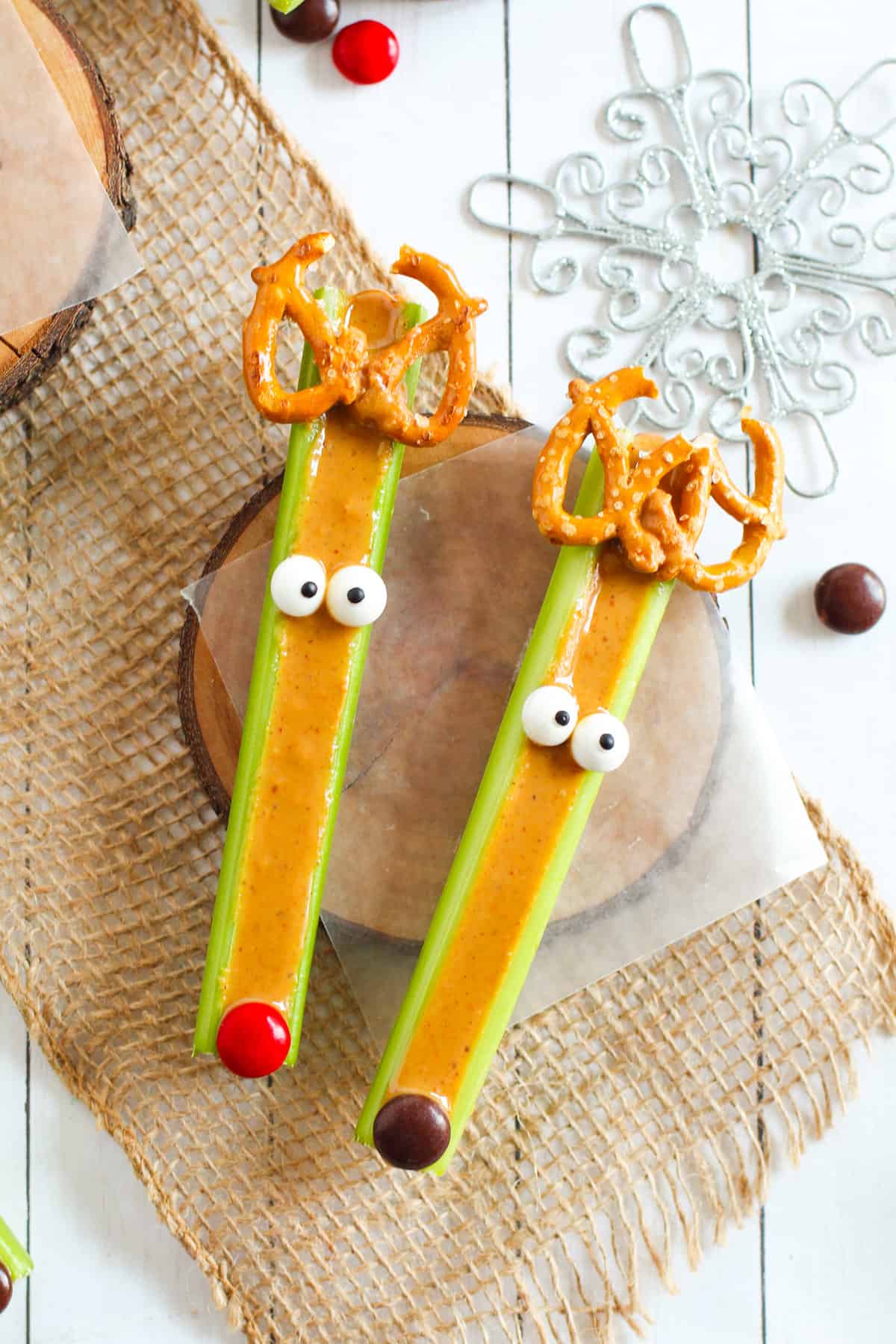 Peanut butter filled celery sticks decorated to look like reindeer with candy eyes, pretzels, and M&Ms.