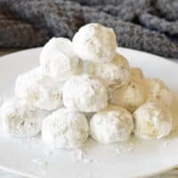 Pecan snowball cookies piled on white serving plate.
