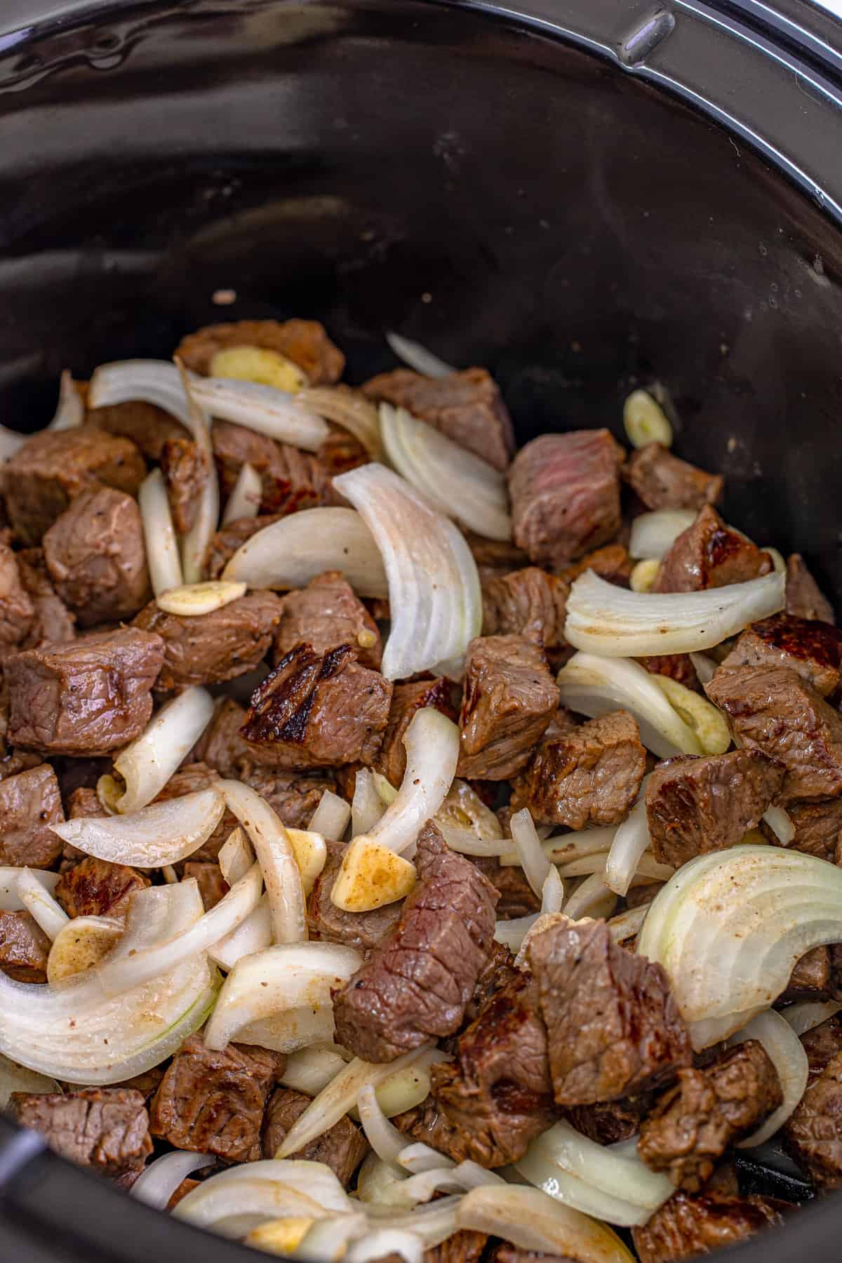 Steak bites with garlic and onions in crockpot.