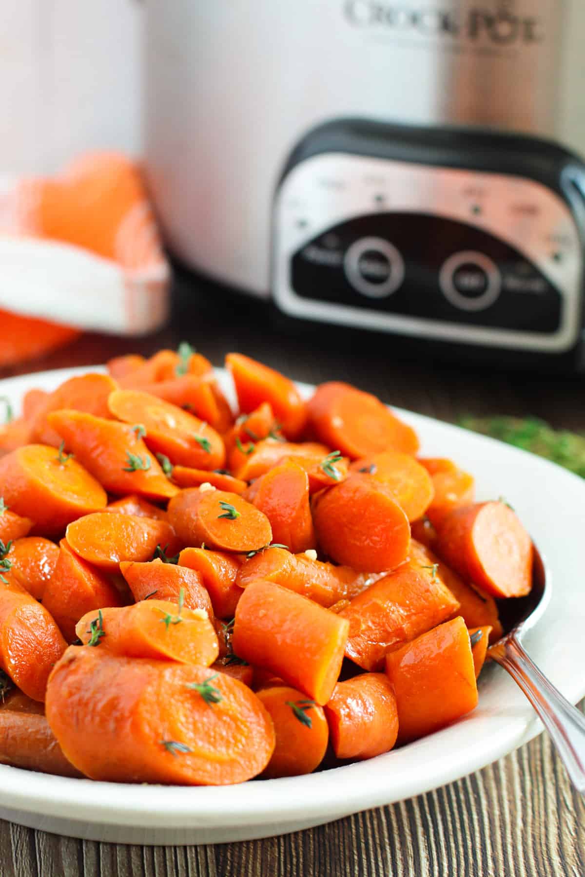 Brown sugar glazed carrots with crockpot behind them.