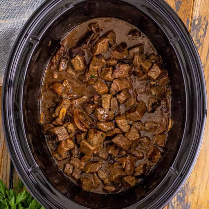 Crockpot steak bites in au jus sauce with garlic and sweet onions.