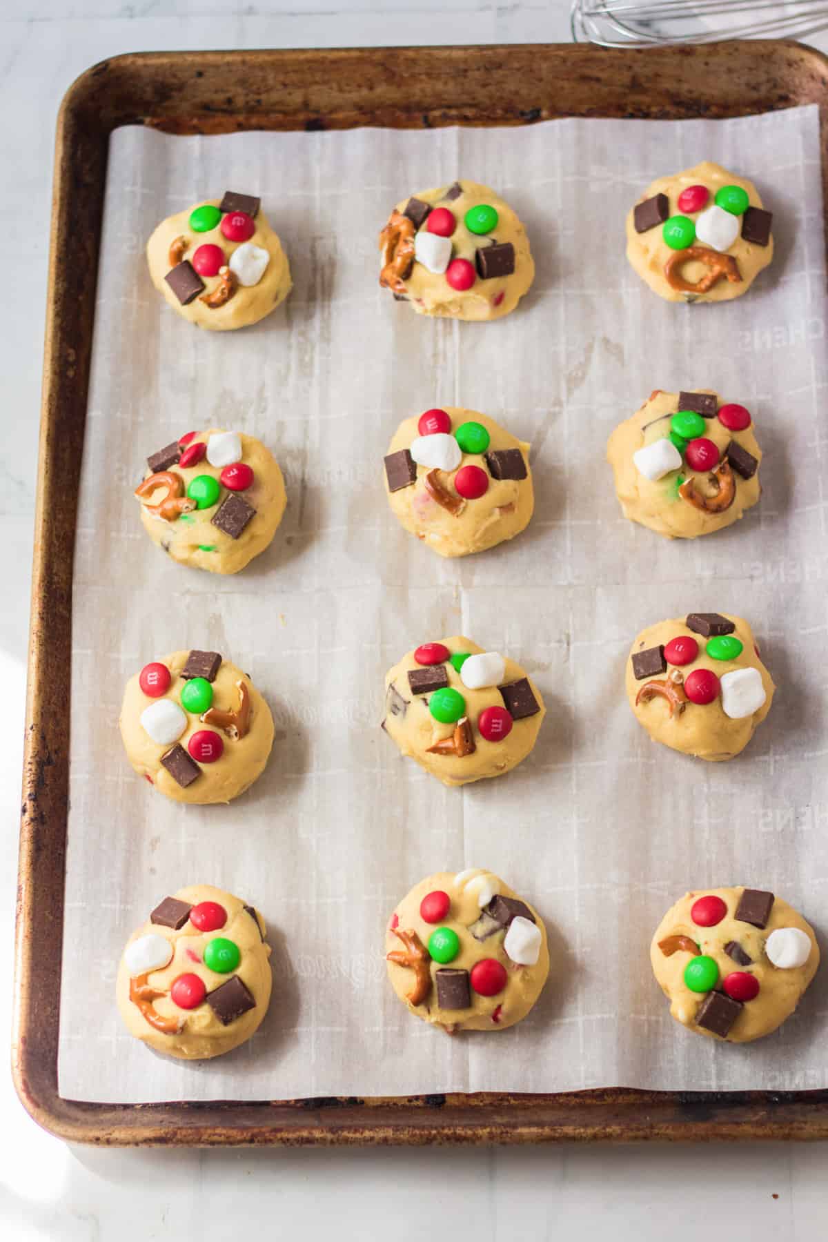 12 cookie dough balls on lined baking sheet.