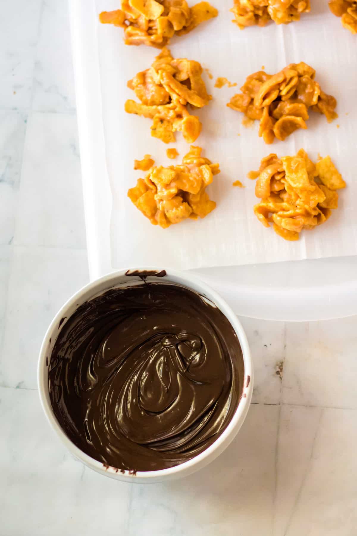 Bowl of melted chocolate next to fritos candy clusters.