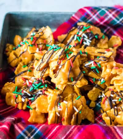 Peanut butter fritos candy topped with a drizzle of chocolate and Christmas sprinkles.