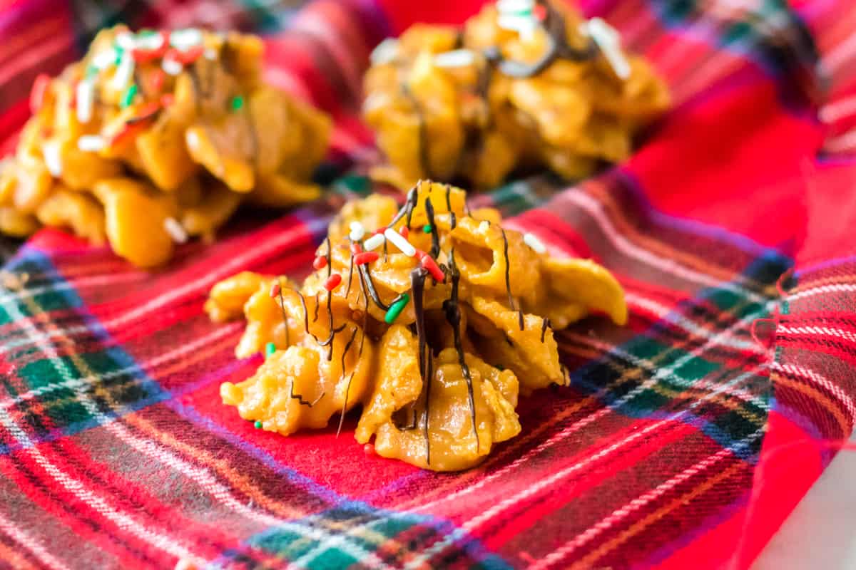 Fritos candy with chocolate drizzle and Christmas sprinkles on red plaid napkin.