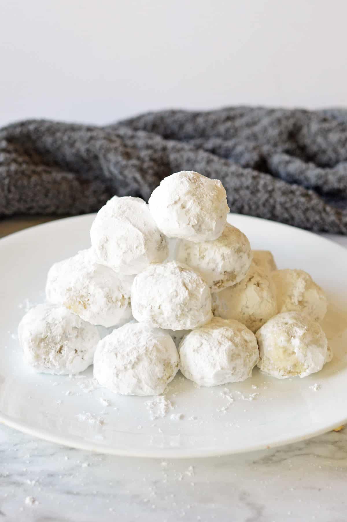 Buttery pecan snowball cookies piled on white serving plate.