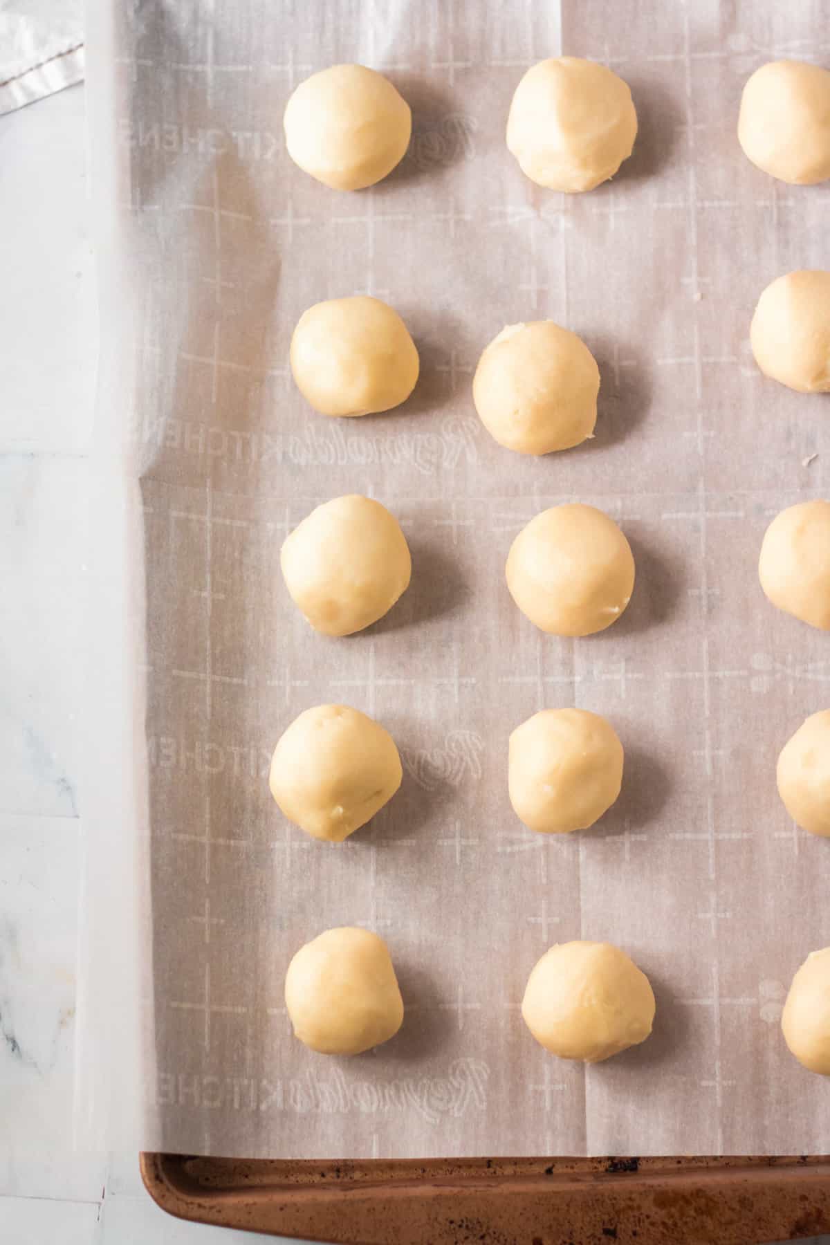 Balls of dough on lined baking sheet.